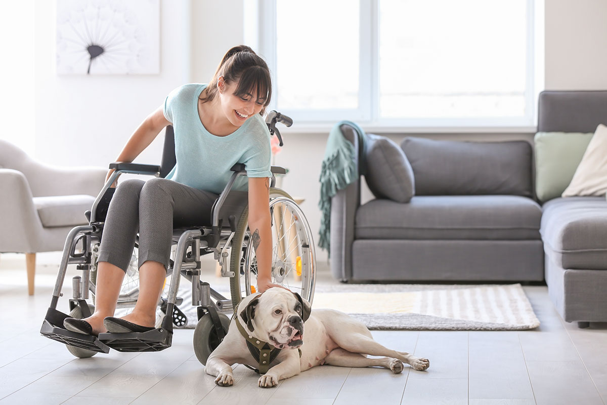 Make-a-Move-With-our-Trusted-ATPs Woman in wheelchair petting her dog laying on living room floor